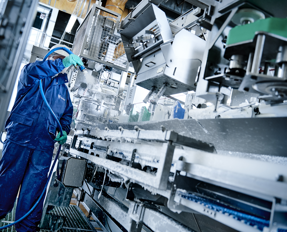 Operator using Foamico low pressure cleaning technology to clean a food production facility