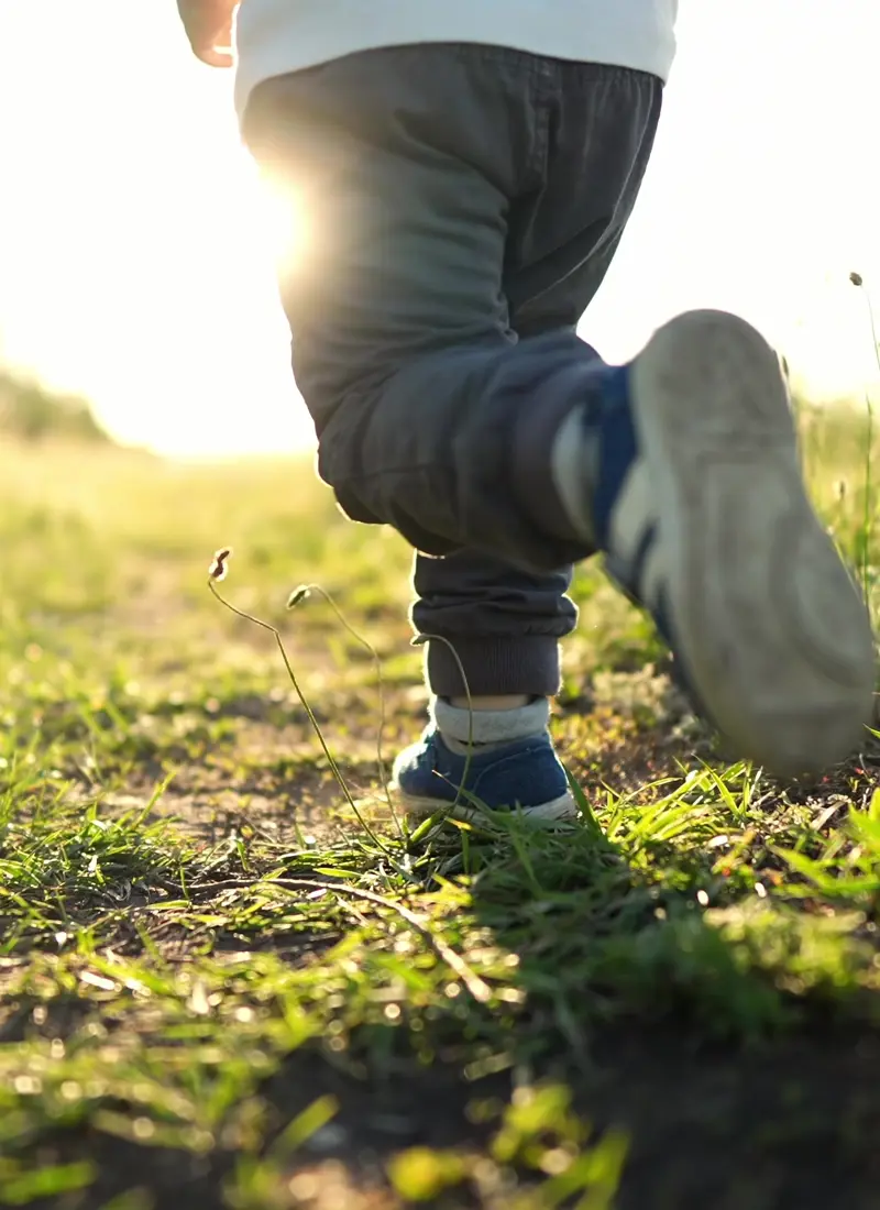 A child running through grass at sunset