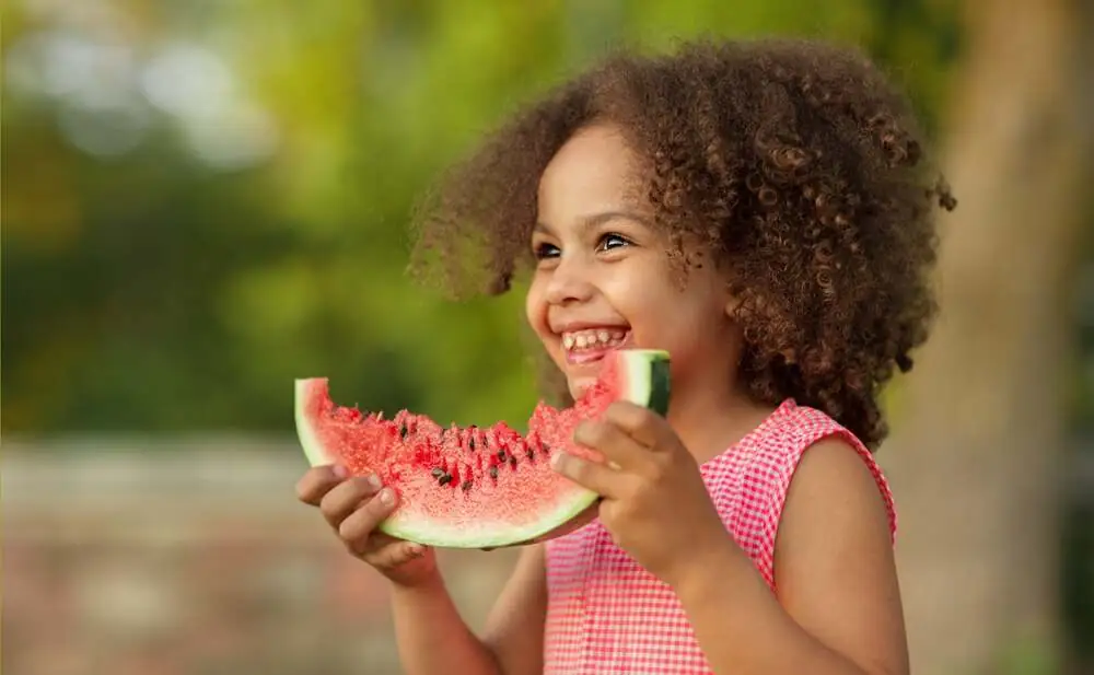 A girl laughing with a slice of watermelon