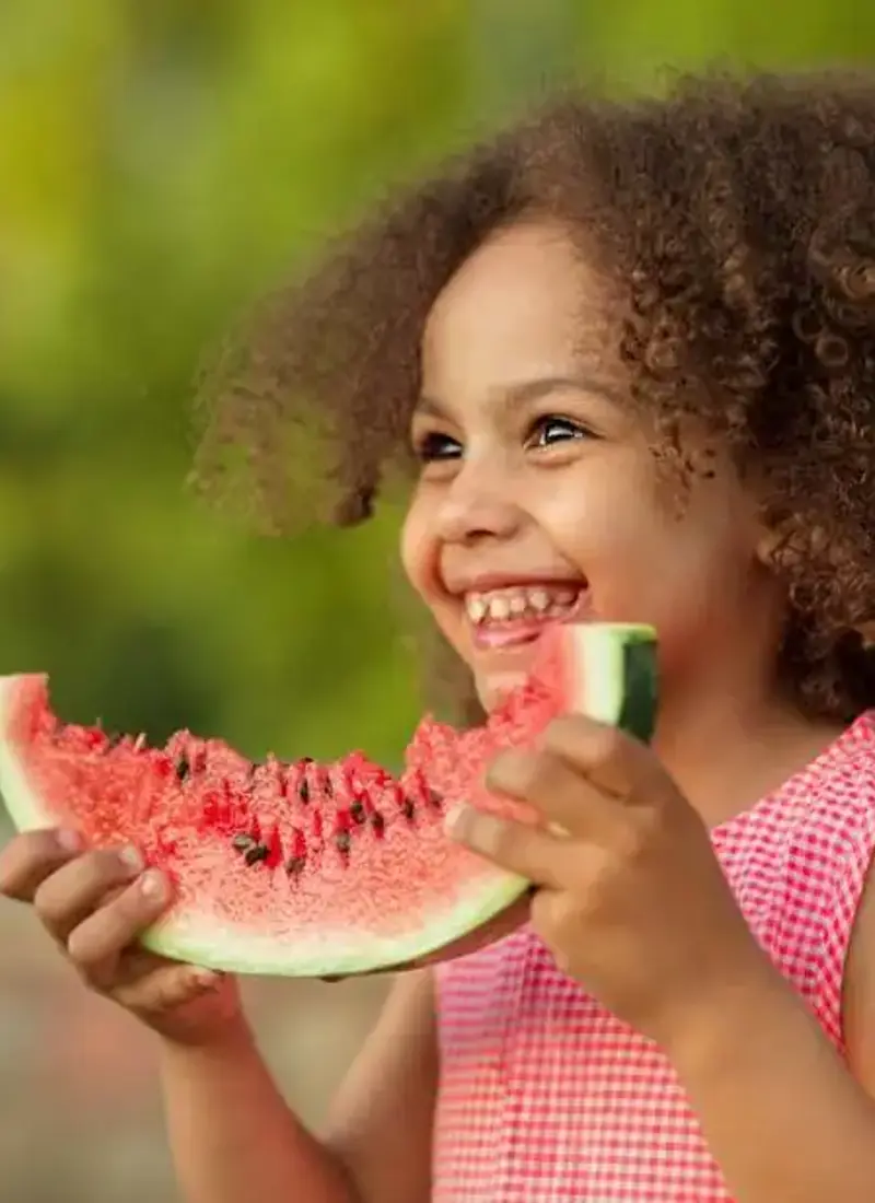 A girl laughing with a slice of watermelon